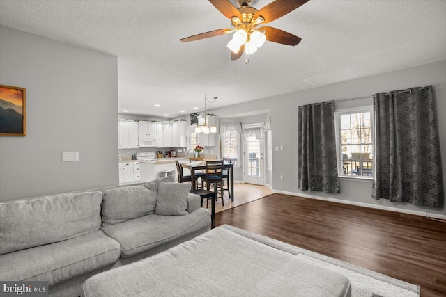 living room featuring light wood-style floors, plenty of natural light, baseboards, and a textured ceiling