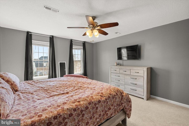 bedroom featuring baseboards, visible vents, a textured ceiling, and light colored carpet