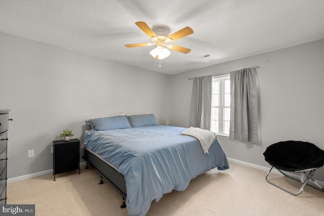 bedroom with light carpet, a ceiling fan, baseboards, and a textured ceiling