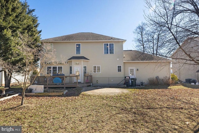 back of property featuring a deck, a patio, and a lawn