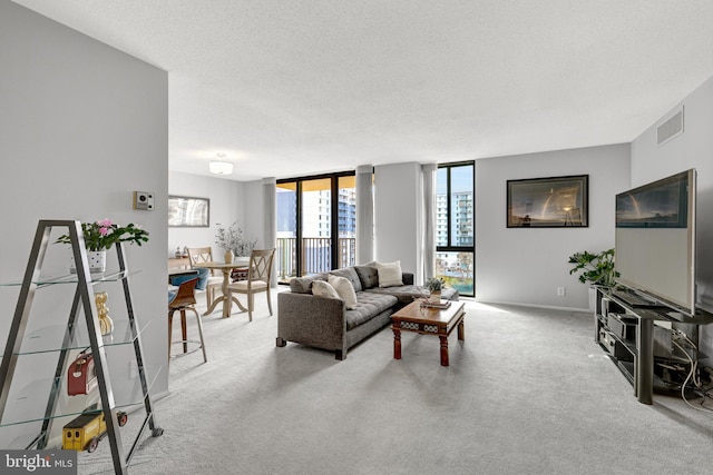 living room with a textured ceiling, light carpet, and floor to ceiling windows