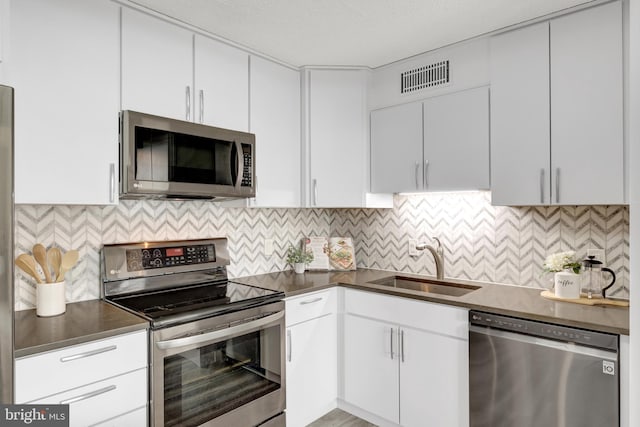 kitchen with sink, appliances with stainless steel finishes, white cabinets, and decorative backsplash