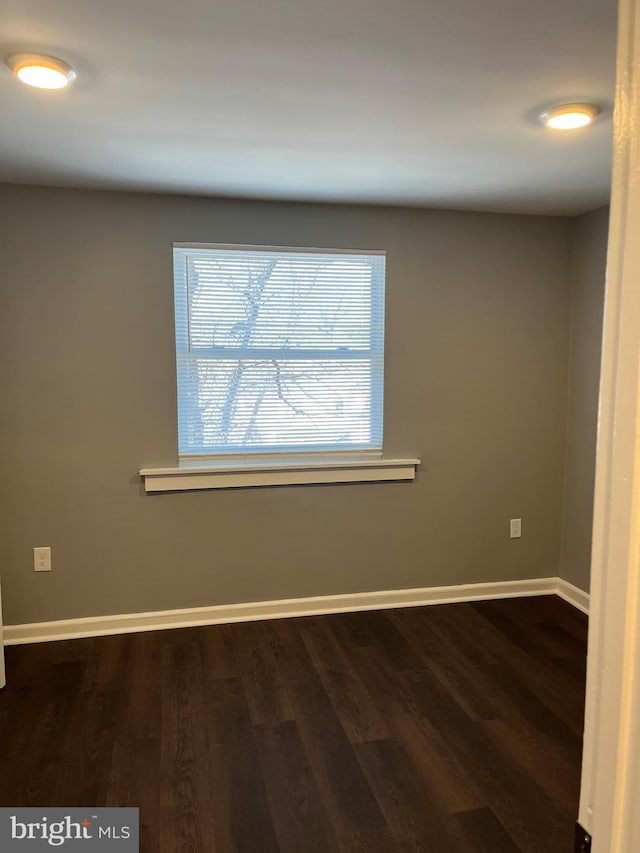 unfurnished room with dark wood-type flooring