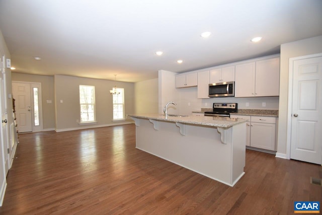 kitchen with stainless steel appliances, an island with sink, sink, and white cabinets