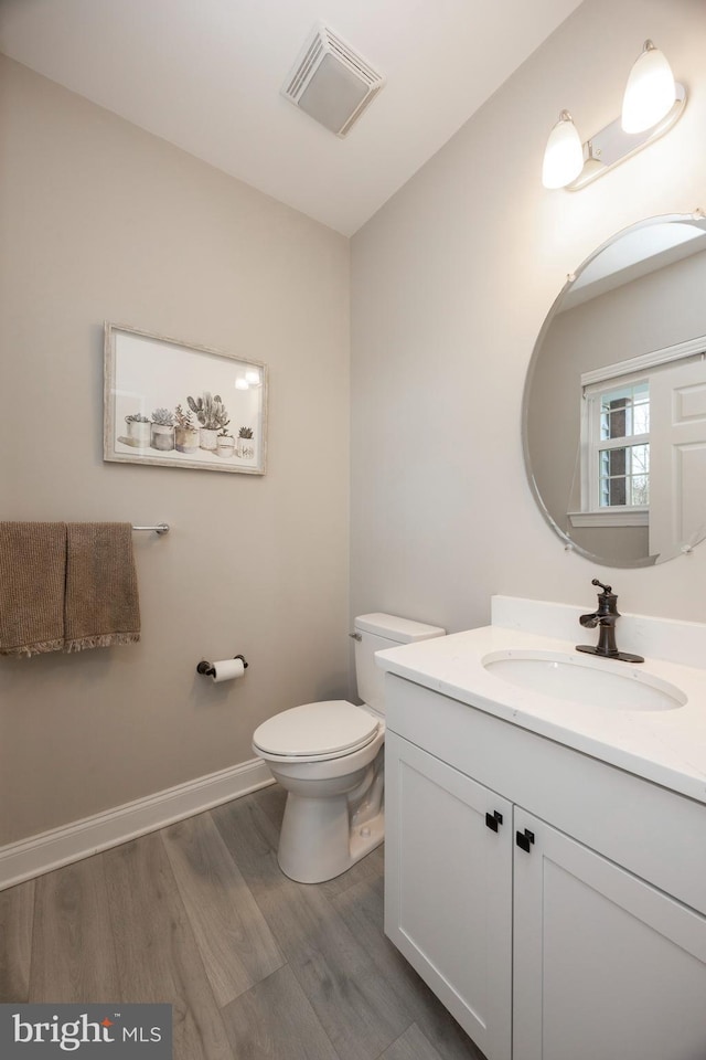 bathroom with toilet, hardwood / wood-style flooring, and vanity