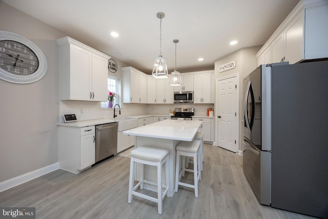 kitchen with light hardwood / wood-style flooring, stainless steel appliances, backsplash, a kitchen island, and white cabinetry