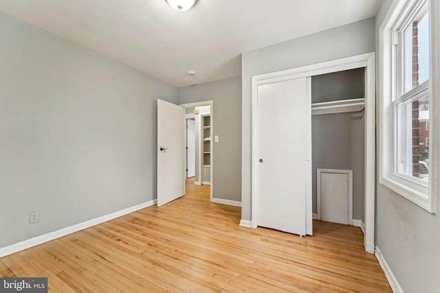 unfurnished bedroom with multiple windows, light hardwood / wood-style floors, and a closet