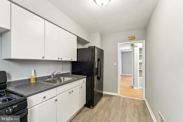 kitchen featuring sink, white cabinets, light wood-type flooring, and black appliances