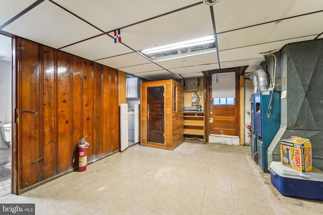 interior space featuring wooden walls, washer / dryer, heating unit, and a drop ceiling