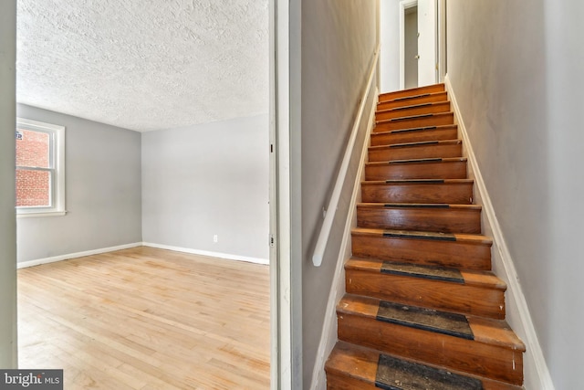 stairs featuring hardwood / wood-style floors and a textured ceiling