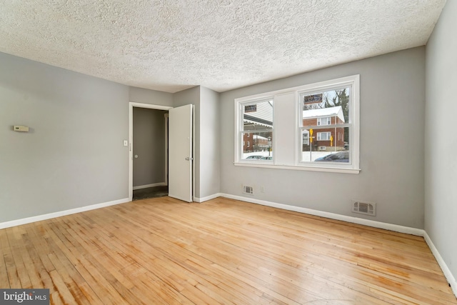 unfurnished room with light hardwood / wood-style floors and a textured ceiling