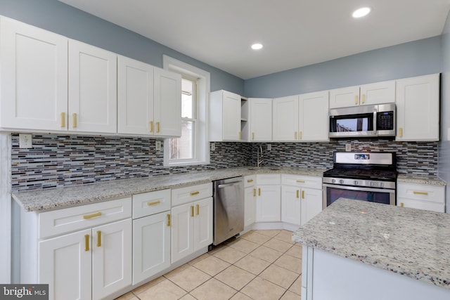 kitchen featuring light stone countertops, appliances with stainless steel finishes, white cabinets, and backsplash