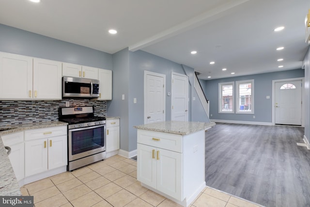 kitchen with white cabinetry, appliances with stainless steel finishes, light stone counters, and decorative backsplash