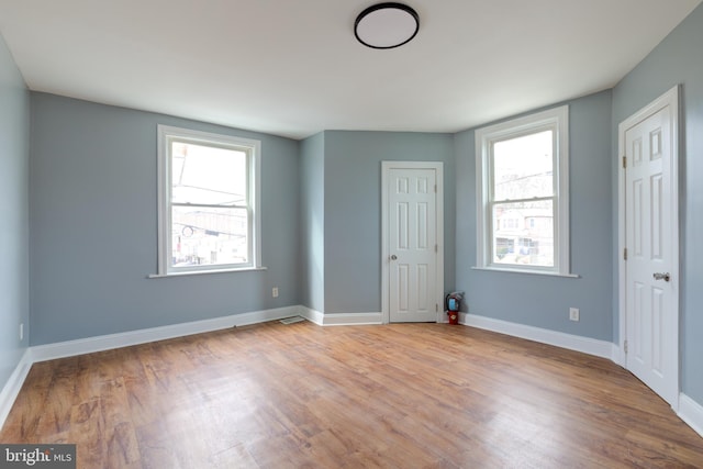 unfurnished bedroom featuring multiple windows and light wood-type flooring