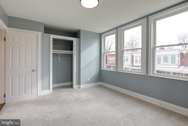 unfurnished bedroom with multiple windows, a closet, and light carpet