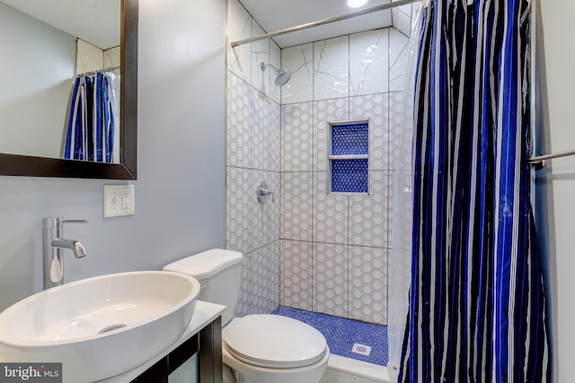 bathroom with sink, a tile shower, and toilet