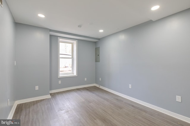 spare room featuring electric panel and light hardwood / wood-style flooring