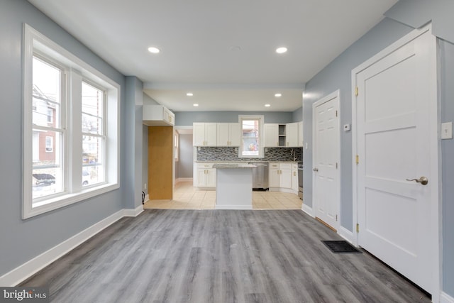 kitchen featuring stainless steel appliances, light hardwood / wood-style flooring, decorative backsplash, and white cabinets