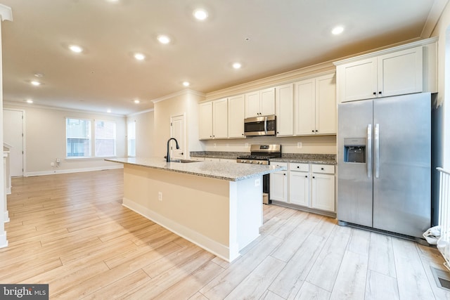 kitchen featuring light wood finished floors, an island with sink, stainless steel appliances, crown molding, and a sink