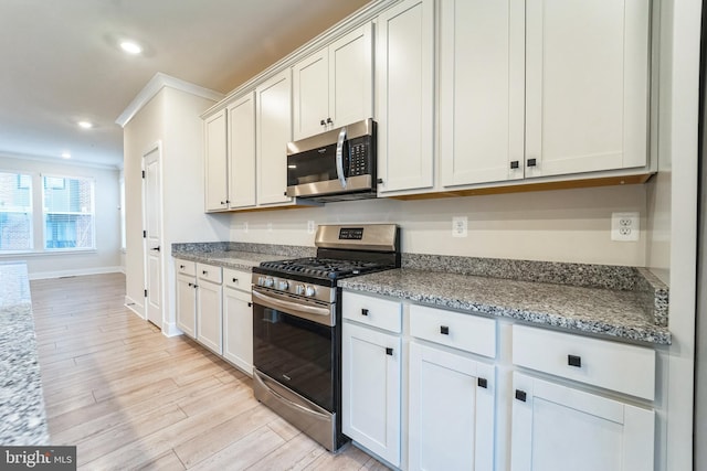 kitchen with appliances with stainless steel finishes, light stone counters, ornamental molding, light wood-style floors, and recessed lighting