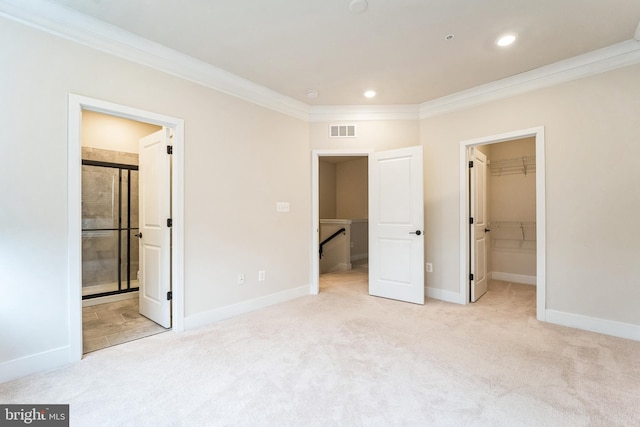 unfurnished bedroom featuring ornamental molding, a walk in closet, visible vents, and carpet flooring