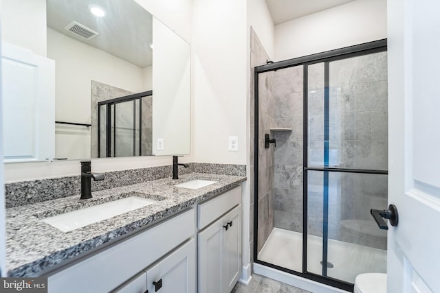 bathroom featuring visible vents, a sink, a shower stall, and double vanity