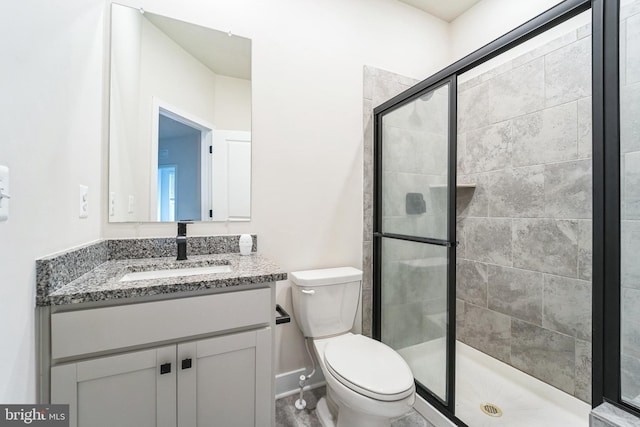 bathroom with a stall shower, vanity, and toilet