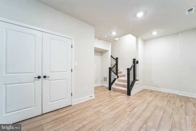 basement featuring baseboards, visible vents, stairway, and light wood finished floors