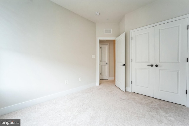 unfurnished bedroom with baseboards, a closet, visible vents, and light colored carpet