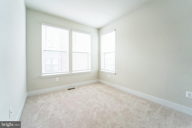 spare room featuring carpet floors, visible vents, and baseboards