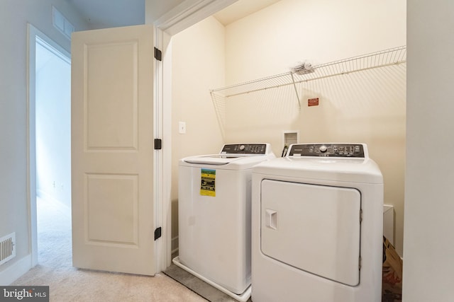 clothes washing area featuring laundry area, visible vents, washer and clothes dryer, and light colored carpet