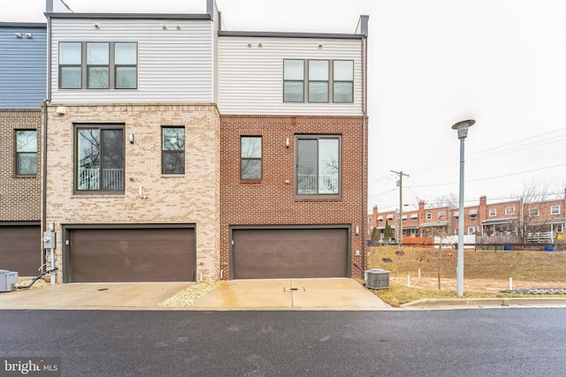 view of front facade featuring driveway, central air condition unit, a garage, and brick siding