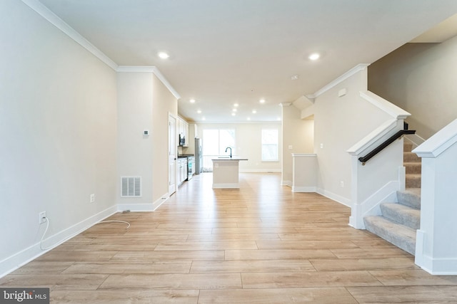 unfurnished living room with ornamental molding, visible vents, stairway, and light wood finished floors