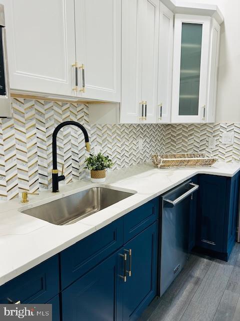 kitchen with blue cabinets, sink, white cabinetry, dishwasher, and backsplash