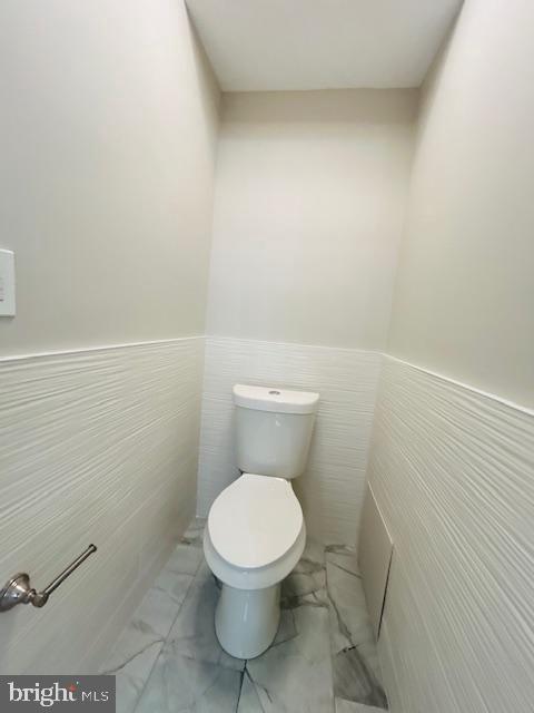 bathroom featuring toilet and tile walls