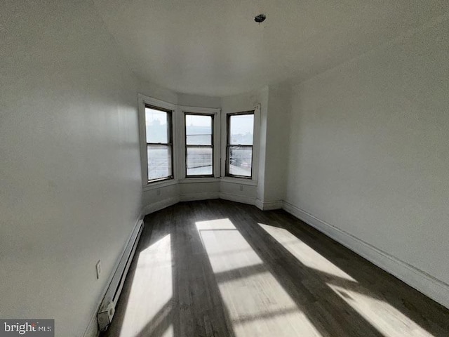 empty room with wood-type flooring and baseboard heating