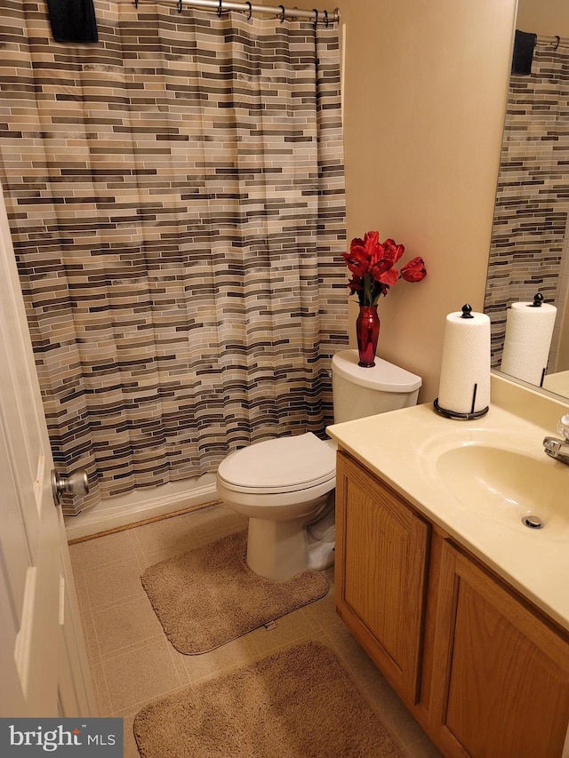 bathroom with a shower with curtain, vanity, toilet, and tile patterned floors