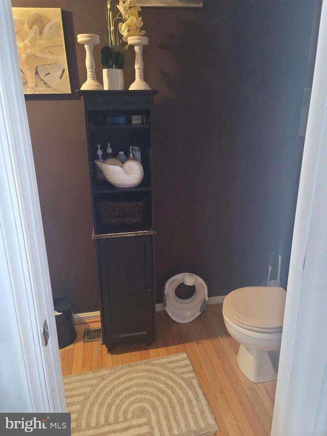 bathroom featuring toilet, baseboards, and wood finished floors