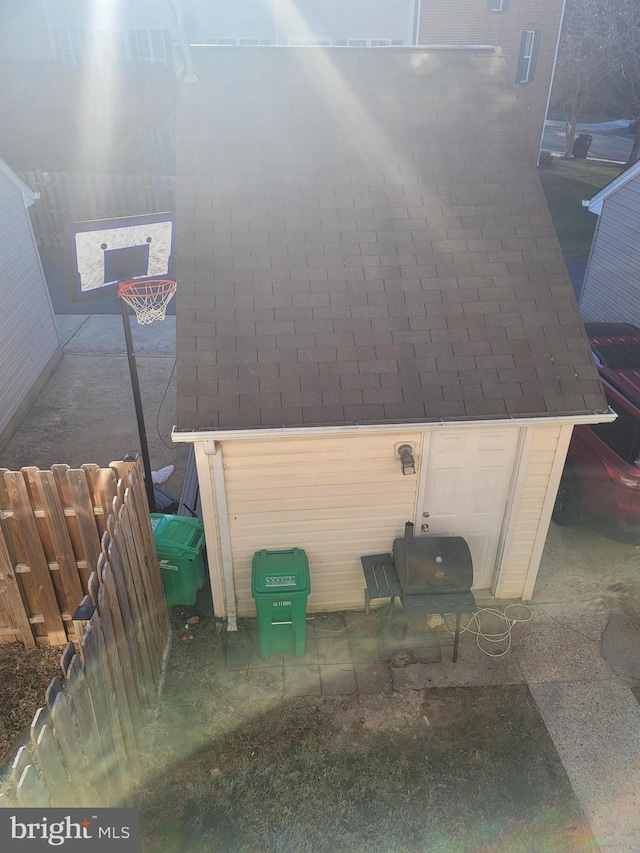 exterior space featuring fence and roof with shingles