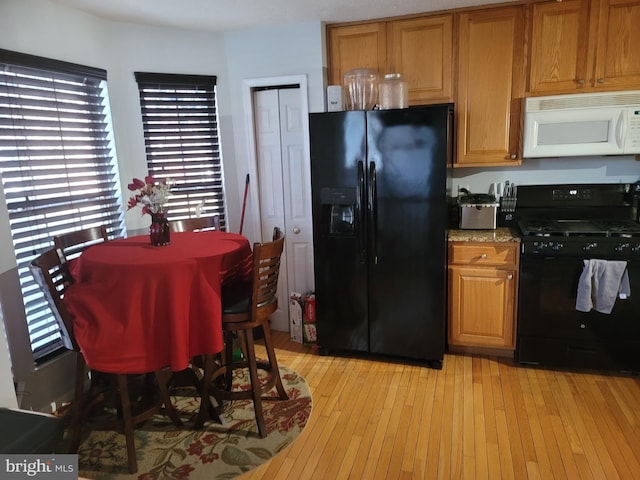 kitchen with light stone countertops, black appliances, light wood finished floors, and brown cabinetry