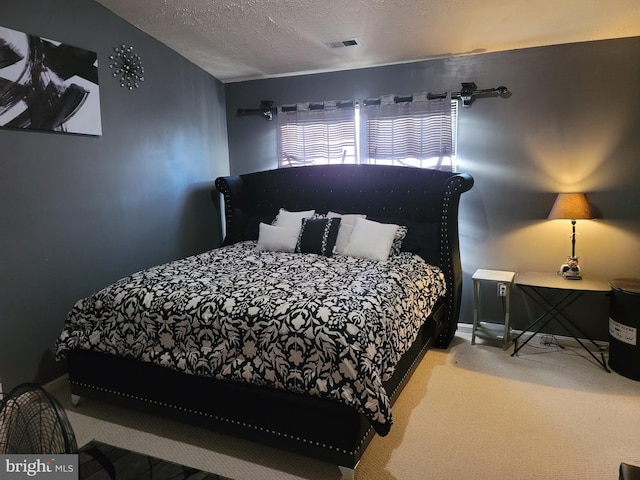 bedroom featuring a textured ceiling, carpet, and visible vents