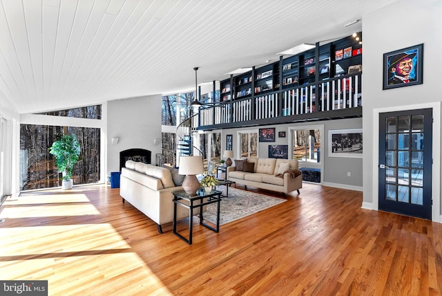 living area with wood finished floors, high vaulted ceiling, wooden ceiling, baseboards, and stairs