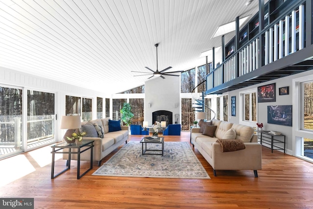 living area with high vaulted ceiling, a ceiling fan, a fireplace, and wood finished floors