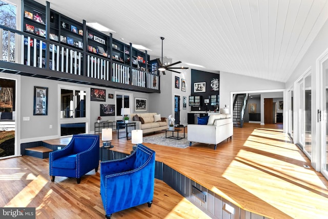 living area with ceiling fan, high vaulted ceiling, and wood finished floors