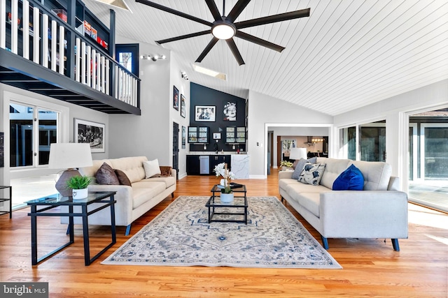 living room featuring high vaulted ceiling, baseboards, and wood finished floors