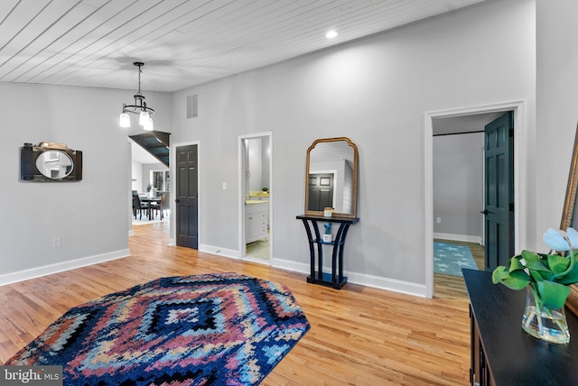 interior space featuring lofted ceiling, light wood finished floors, baseboards, and visible vents