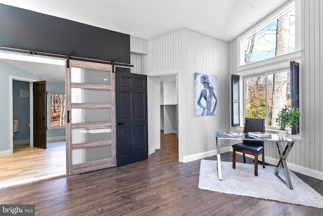 office space featuring a barn door, baseboards, and wood finished floors