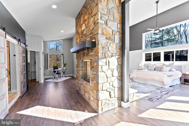 unfurnished living room with ceiling fan, a barn door, a towering ceiling, and hardwood / wood-style floors