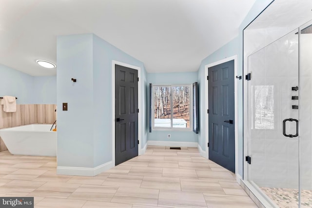 full bath featuring a stall shower, a freestanding tub, lofted ceiling, and baseboards