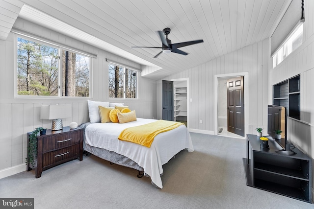 bedroom featuring carpet, a walk in closet, multiple windows, and lofted ceiling